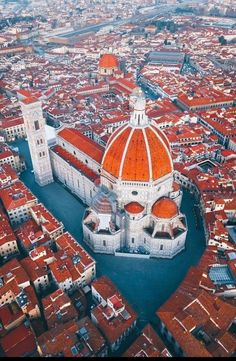 an aerial view of a city with red roofs and tall buildings in the foreground