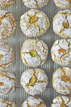 there are many powdered sugar covered cookies on the cooling rack with pistachios