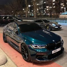 a blue car parked on the side of a road next to other cars at night