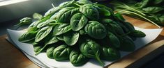 a pile of green leaves sitting on top of a cutting board next to a window