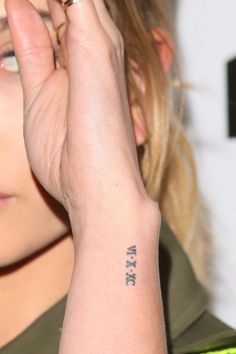 a close up of a person with a tattoo on her wrist and hand holding something in the air