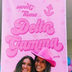 two women standing next to each other in front of a pink sign that says sweet home delta gamma