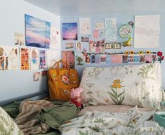 a bed with many pictures on the wall above it and a purse sitting on top of it