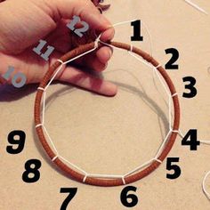 a hand is holding a piece of wood with numbers on it and threading together