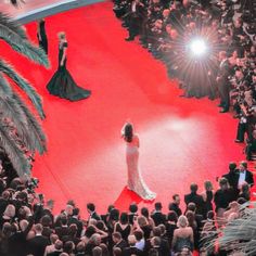 a woman is walking down the red carpet in front of an audience at a fashion show