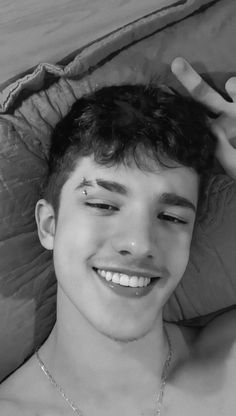 black and white photograph of a young man laying in bed with his hand on his head