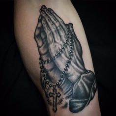 a black and white tattoo of a praying hand with beads on it's arm