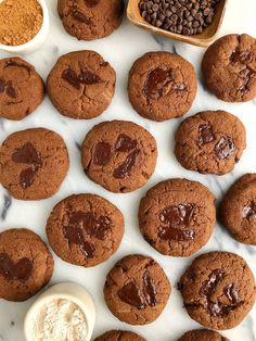 chocolate cookies and other desserts on a marble counter top with bowls of powdered sugar