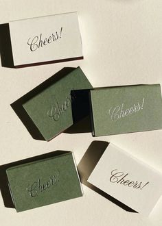 four place cards sitting on top of each other with the word cheers in cursive writing