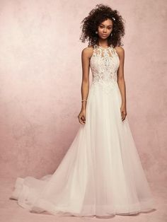 a woman in a white wedding dress posing for a photo against a pink background with her hands on her hips