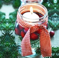 two mason jars filled with cherries and a candle