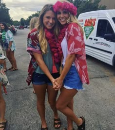 two young women standing next to each other in front of a van and holding hands