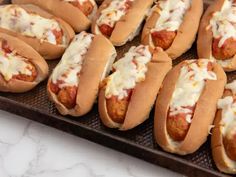 many hot dogs with toppings are lined up on a tray