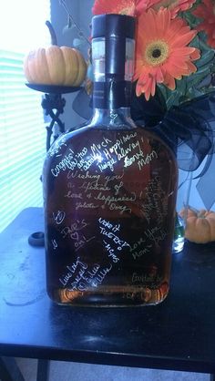 a bottle with writing on it sitting next to flowers