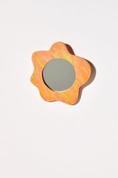 an orange and pink flower shaped mirror on a white surface