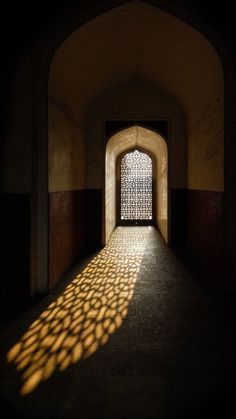 an arched doorway with the light coming through and casting a shadow on the wall behind it