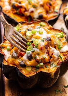 a fork in a baked potato dish with cheese and other toppings on the side