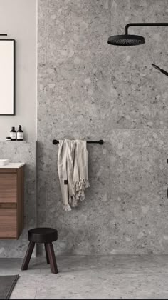 a bathroom with marble walls and flooring, including a black shower faucet