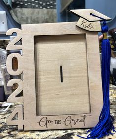 a wooden frame with a graduation cap and tassel hanging from the front, on a table