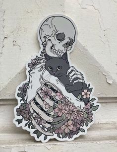 a sticker depicting a skeleton holding a black cat with flowers on it's chest