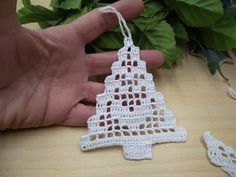 a crocheted christmas tree ornament being held by someone's hand