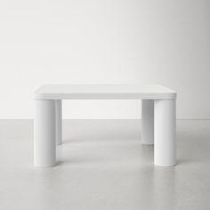 a white table sitting on top of a cement floor next to a wall in an empty room