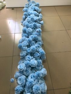 blue flowers are arranged in the shape of a long line on the floor next to a wall