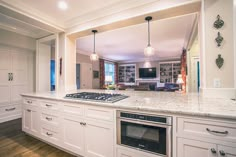 a large kitchen with white cabinets and marble counter tops, along with an island in the middle