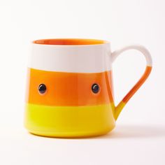 an orange and white striped coffee mug with eyes on the inside, sitting against a white background