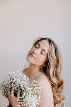 a woman with her eyes closed holding a bouquet of baby's breath