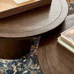 a wooden table sitting on top of a blue rug next to a book and magazines