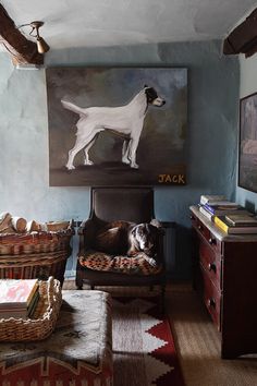 a dog is laying on a chair in the living room with a painting behind it