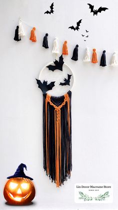 a halloween decoration with bats and tassels hanging on the wall next to a pumpkin