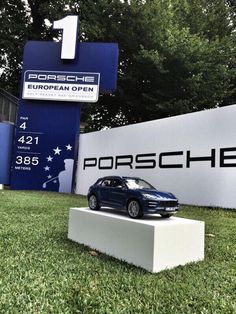 a car is on display in front of the porsche dealership sign at its showroom