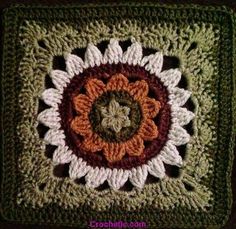 a crocheted square with an orange and white flower