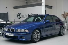 a blue car parked in front of a white wall with automotns on it