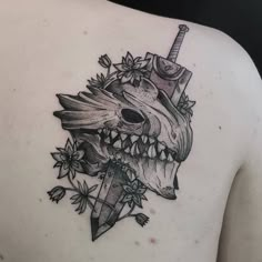 the back of a woman's shoulder with a skull and dagger tattoo on it