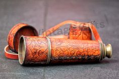 an orange leather case with gold trimmings sits on the ground next to two rolls of tape