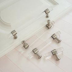 four pieces of glass with metal handles on a white counter top next to a sink