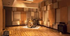 an empty room with wood paneling and drum set up on the floor in front of it