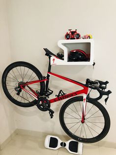 a red bike leaning up against a white wall next to a pair of black shoes