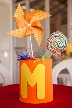 a paper pinwheel and lollipops in a cup on a red table