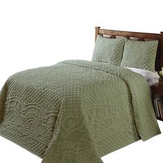 a bed with green bedspread and pillows on top of the headboard next to a night stand