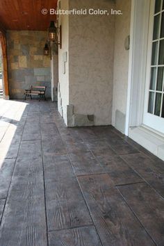 a porch with wood flooring and white trim on the side of it, next to an open door