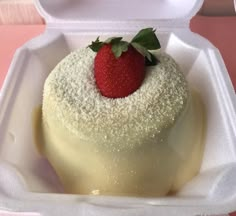 a small dessert in a foam container with a strawberry on top