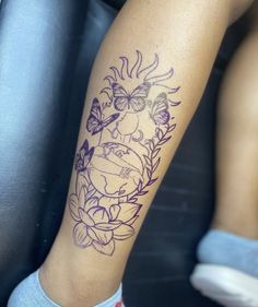 a woman's leg with a tattoo on it that has flowers and butterflies in the center