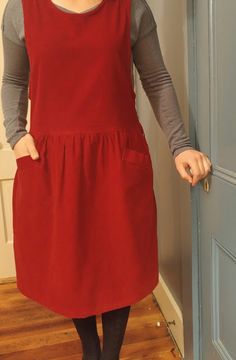 a woman standing in front of a door wearing a red dress and black tights