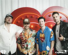 three men standing next to each other in front of a backdrop