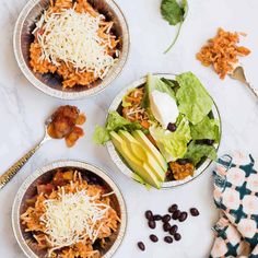 three bowls filled with food sitting on top of a white counter next to utensils