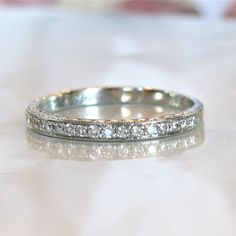 a close up view of a wedding ring on a white surface with the background blurry